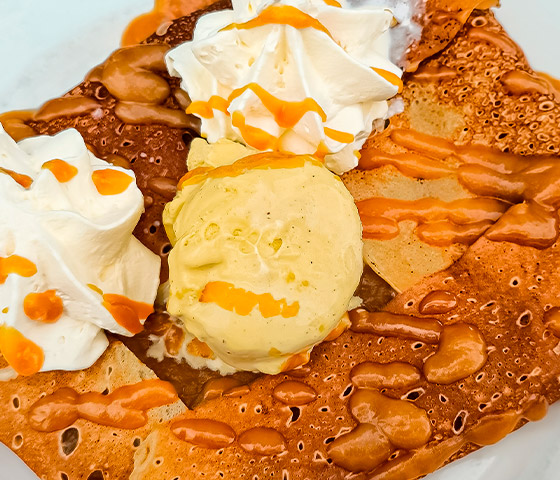 Crêpe sucrée nappée de caramel et garnie d'une boule de glace vanille, spécialité maison Crêperie Les Deux Frères